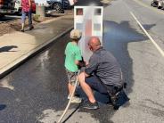 Firefighter training child on how to use a fire hose